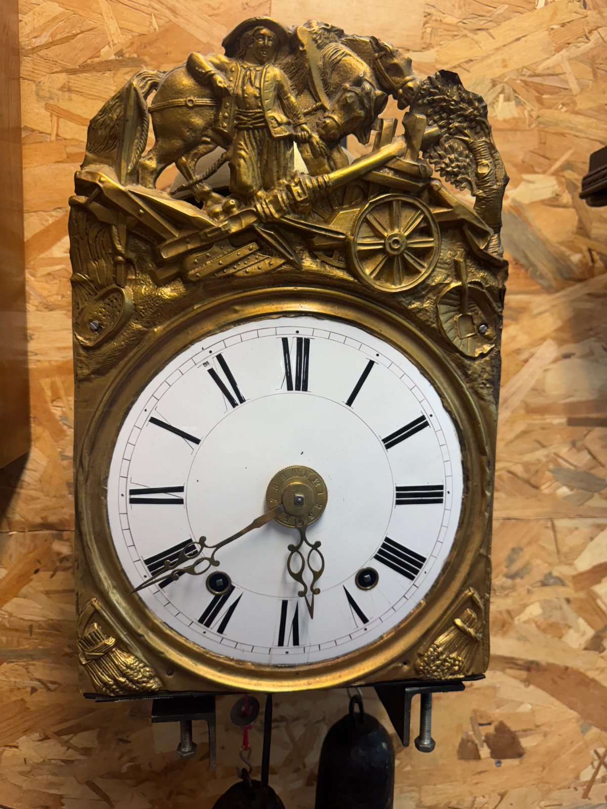 Cadran de laiton et rouages d’un mouvement d’horloge sur l’établi de l’horloger