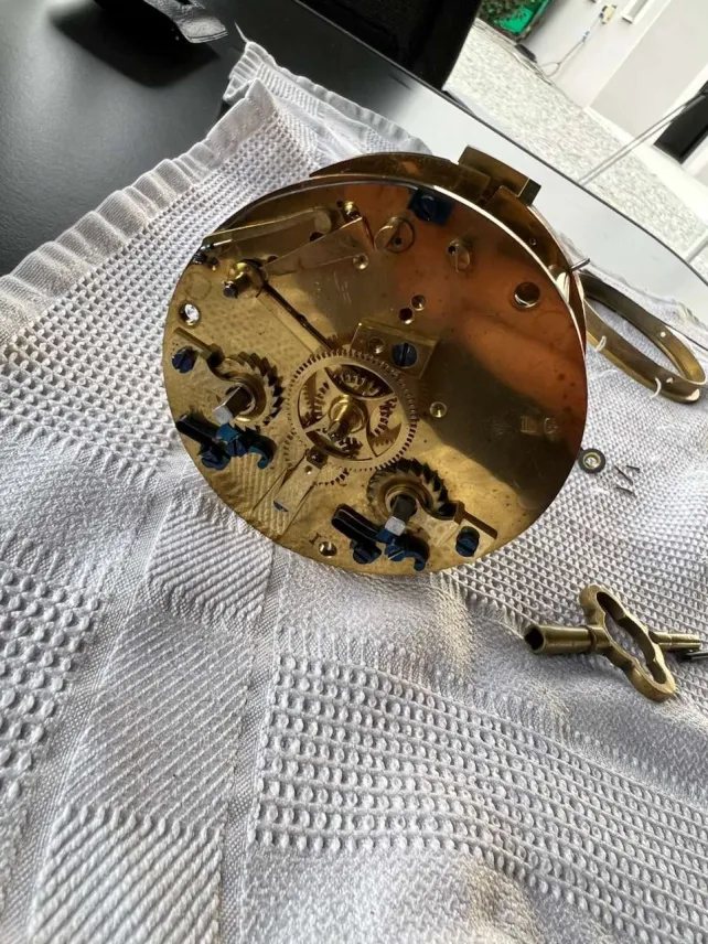 Mouvement d’horlogerie démonté, pièces disposées sur un plateau d’atelier